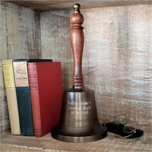  13 inch tall antiqued brass and wood hand bell on shelf with glasses and books