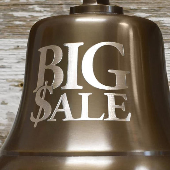 Closeup of words BIG SALE engraved on front of a 7 inch antiqued brass wall bell