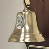 Closeup of oval cancer ribbon pewter medallion mounted on a polished finish brass bell