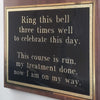 Closeup of large gold and black plate with saying "ring this bell, three times well, to celebrate this day.  This course is run, my treatment done, now I am on my way."