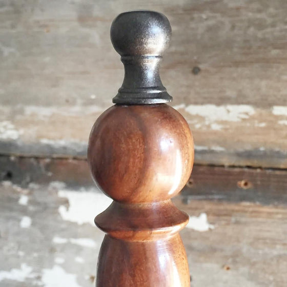Closeup of brass finial on top of wood hand bell handle