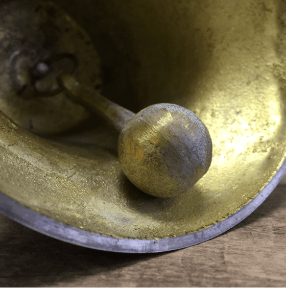 Closeup of clapper inside a brass hand bell