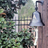 10 inch diameter dark bronze wall bell hanging on rustic wood with fence  in background
