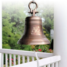  18 inch diameter personalized antiqued finish solid brass bell with round shackle on top hanging from a front porch outside