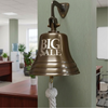 7 inch antiqued brass wall bell with words BIG SALE engraved on it hanging in an office