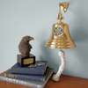 7 inch polished brass wall bell hung on blue wall by eagle sculpture and three books