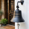 Dark bronze wall bell with engraved family name and address mounted outside a front door
