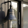 Dark bronze wall bell with engraved family name and address mounted outside a front door