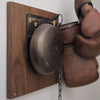 Replica distressed finish brass boxing bell on wood plaque with boxing gloves hanging nearby