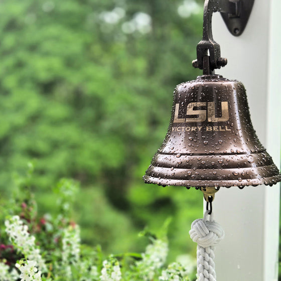 LSU Victory Bell with raindrops against a blurred green background