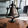 Large dark brown replica railroad bell with engraved logo on a wood base
