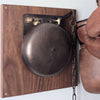 Replica distressed finish brass boxing bell on wood plaque with boxing gloves hanging nearby