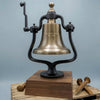 A brass railroad bell on a black metal mounting frame with a wooden base, photographed against a soft blue-gray studio background. The bell is engraved with 'UNION STATION St.