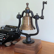  Decorative replica rail bell on a wooden base with a vintage typewriter in the background