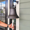 10 inch diameter wall bell hung by front door with hand  on pull rope