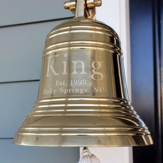 Closeup of 10 inch diameter polished finish solid brass bell with multiple ridge design and three lines of text showing name, established date and city