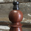 Closeup of a bronze color finial atop the walnut stained hardwood handle of an 11 inch hand bell