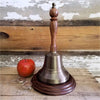 11 inch tall antiqued brass hand bell with optional circular wood base and apple, glasses for size context