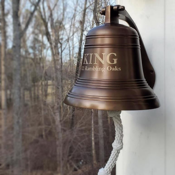 12 inch ridged antique finish wall bell mounted on outside wall with two lines of optional text featuring last name and address