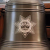 Closeup of a large Police Academy logo engraved on the front of a 14 inch diameter ridged brass bell