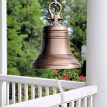  18 inch diameter antiqued finish solid brass bell with round shackle on top hanging from a front porch outside