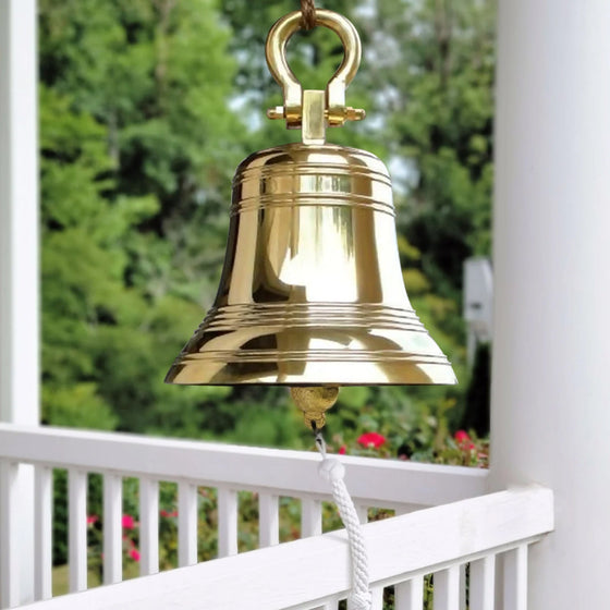 Large 18 inch polished brass ridged bell hanging from shackle on porch