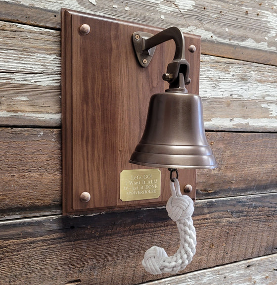 Five inch diameter antiqued brass wall bell mounted on a walnut wood plaque with brass nameplate and custom engraving