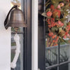 6 inch antiqued brass ridged wall bell with two lines engraving on front outdoor wall by door