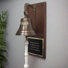  7 inch antiqued brass finish brass wall bell with an engraved business logo mounted on a walnut wood plaque with a black and gold large engraved plate