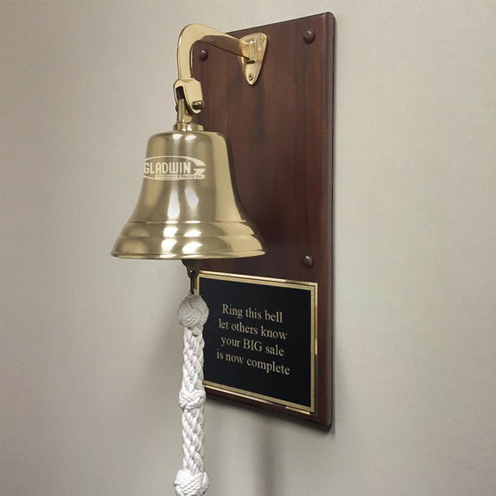 7 inch diameter polished finish solid brass wall bell mounted on a walnut wood plaque with a business logo engraved on the bell and a motivational sales message engraved on a large black and gold metal plate