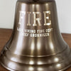 Closeup of engraving on an antiqued finish solid brass seven inch wall bell with word FIRE in large font and two lines of personalized engraving underneath of a fire department and fire chief name
