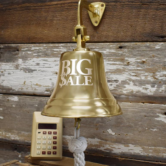 7 inch diameter highly polished finish solid brass wall bell with words BIG $ALE engraved in large font on two lines and a vintage calculator in background