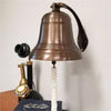 8 inch diameter antiqued finish solid brass ridged wall bell with antique candlestick phone and glasses for size perspective