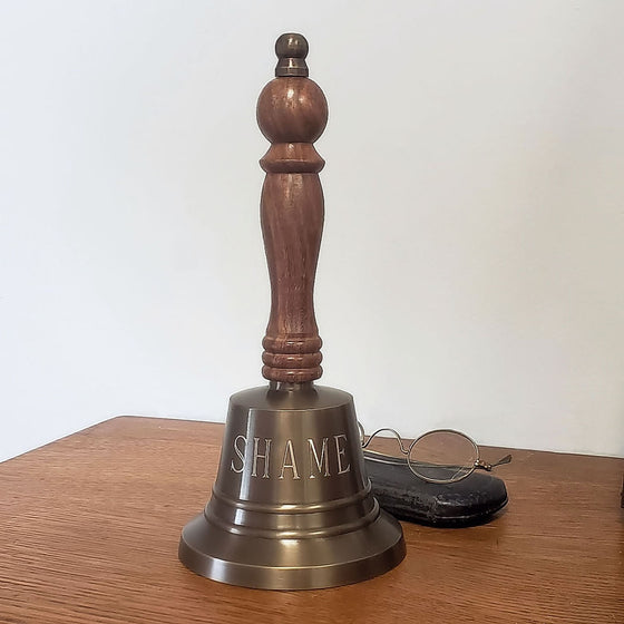 9 inch tall antiqued brass hand bell with wood handle and word "SHAME" engraved in large font on one side