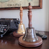 9 inch tall antiqued brass and wood hand bell shown with optional logo engraving and deluxe round walnut base