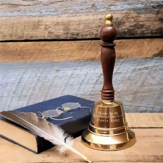 9 inch tall polished finish brass and wood hand bell with three lines of optional engraving and a pair of glasses for size reference
