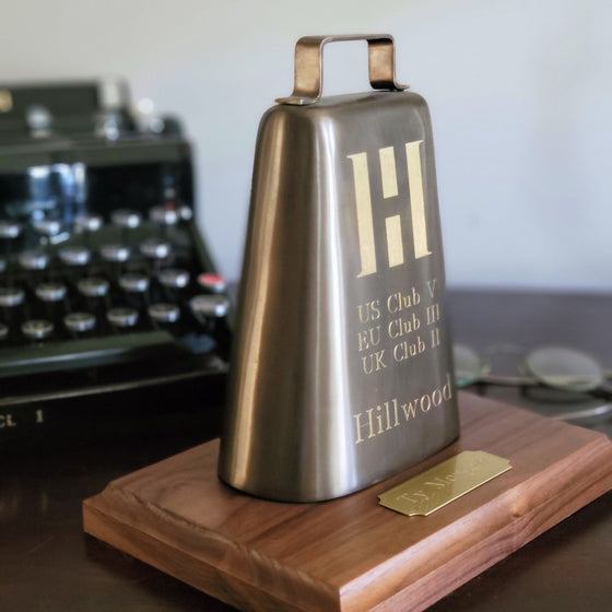 Solid brass replica cow bell with logo and text engraving displayed on optional base with optional brass nameplate