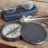Non-engraved plain three inch diameter antiqued brass compass with cover off and vintage glasses in background