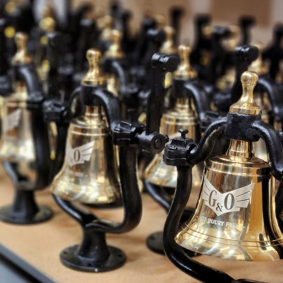 Large order of polished brass medium railroad bells with customer logos engraved being prepared for shipping