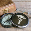 Antiqued brass finish three inch diameter working compass with engraved medical Cardecus on front lid and wood display box