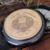 Closeup of antiqued brass color pewter Coast Guard medallion on three inch diameter compass top