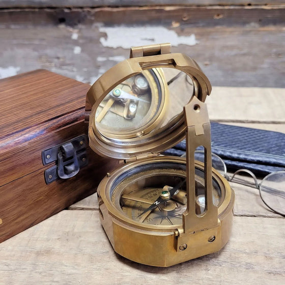 Closeup of a 3 inch antiqued brass military compass partially open, with mirror and compass interior showing